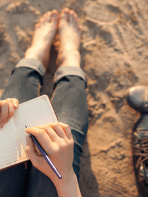 girl writing on beach